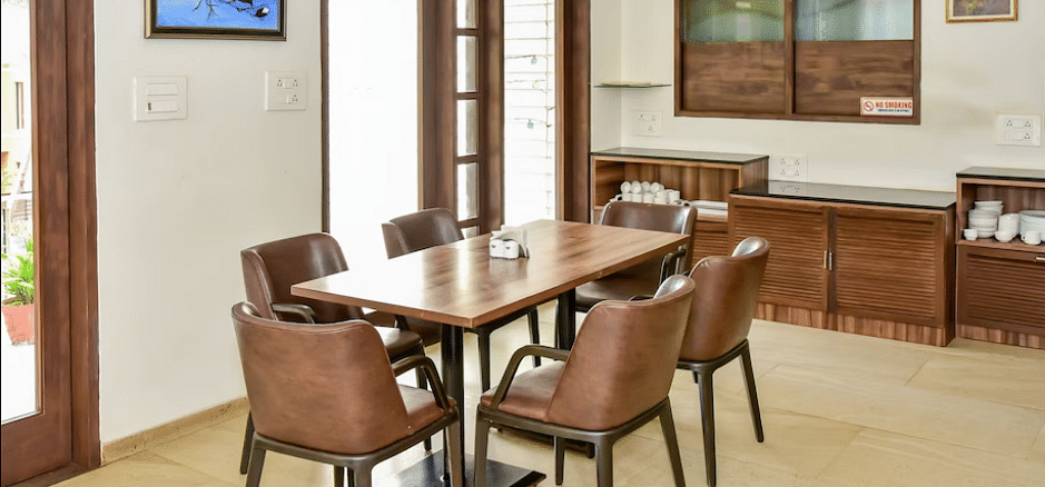 Dining area with a wooden table and chairs, part of the inn's interior at La Vida Studio Inn Goa.