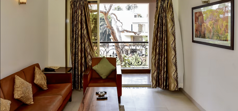 Living area with a sofa, table, and balcony view at La Vida Studio Inn Goa.