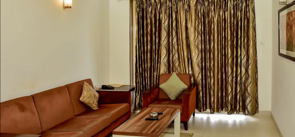 Spacious living area with cushioned sofa set, coffee table, curtained window, and warm lighting at La Vida Studio Inn.