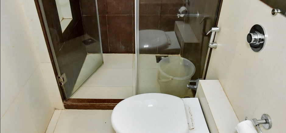 Bathroom with a toilet and shower at La Vida Studio Inn Goa.