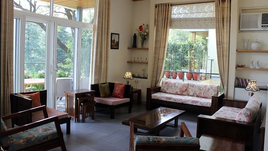 side angle view of a spacious living room with modern interior decor and large windows facing the tea gardensLiving RoomLiving Room4 - Lamrin Norwood Green Palampur
