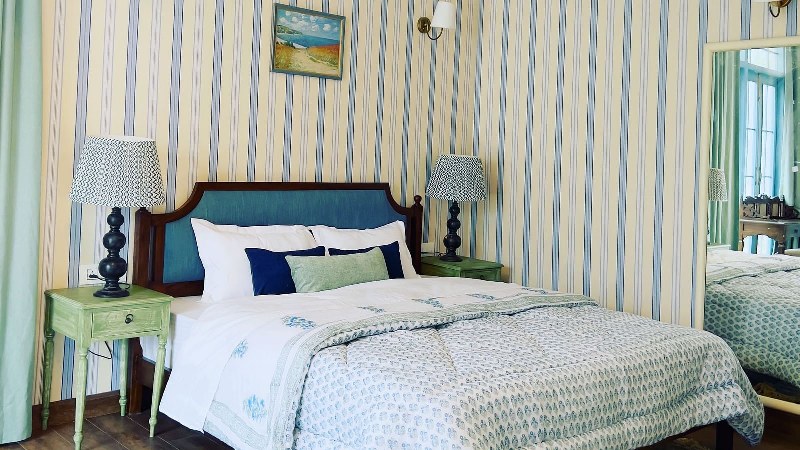 A minimalistic bedroom that has a bedside table and lamp, and a mirror on he wall | Faraway Cottages, Auli
