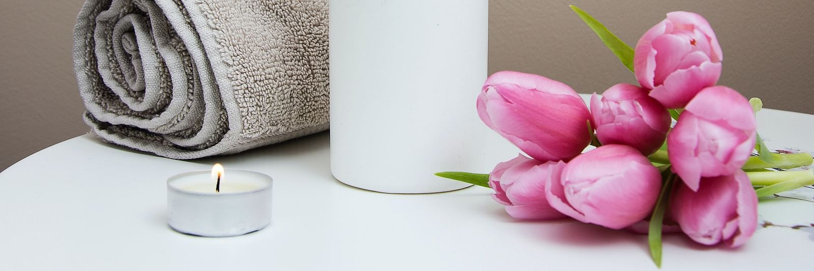 A table with flowers, candle and a fresh towel