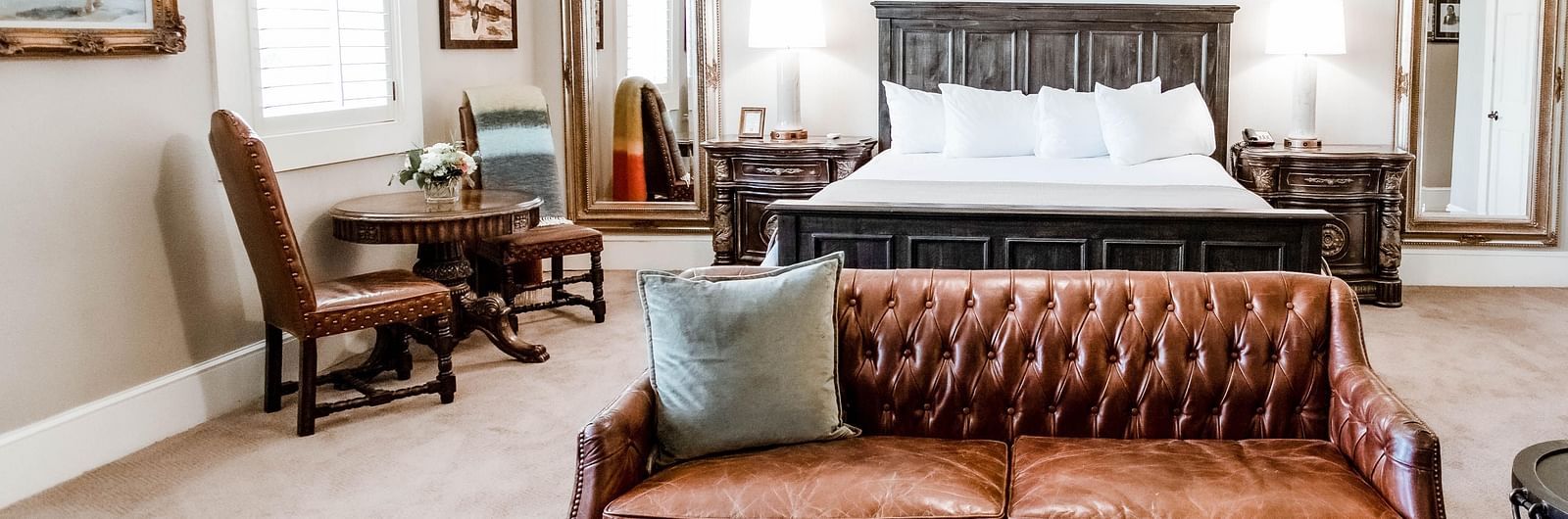 A luxurious bedroom featuring a leather sofa, wooden furniture, and stylish accents, designed for comfort and sophistication - The Grand Hotel & Ballroom, McKinney