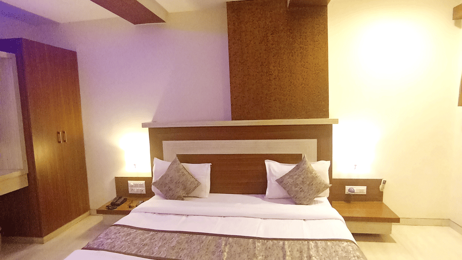 Vertical shot of the suite room featuring a double bed, wood paneled accents, and tile flooring.