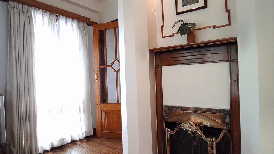 Lobby and Interior corner of the Executive Suite at Cedar Inn featuring wooden flooring, a fireplace setup, framed artwork, and large windows with curtains.