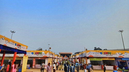 An overview of a fair ground with stalls on either side and people walking in the centre