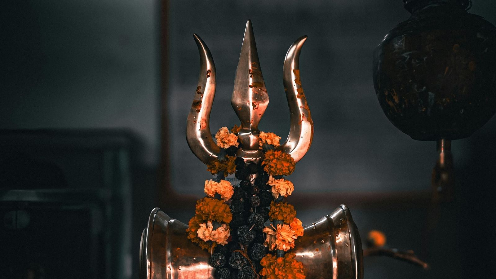 Golden trident with intricate detailing, illuminated against a dark background.