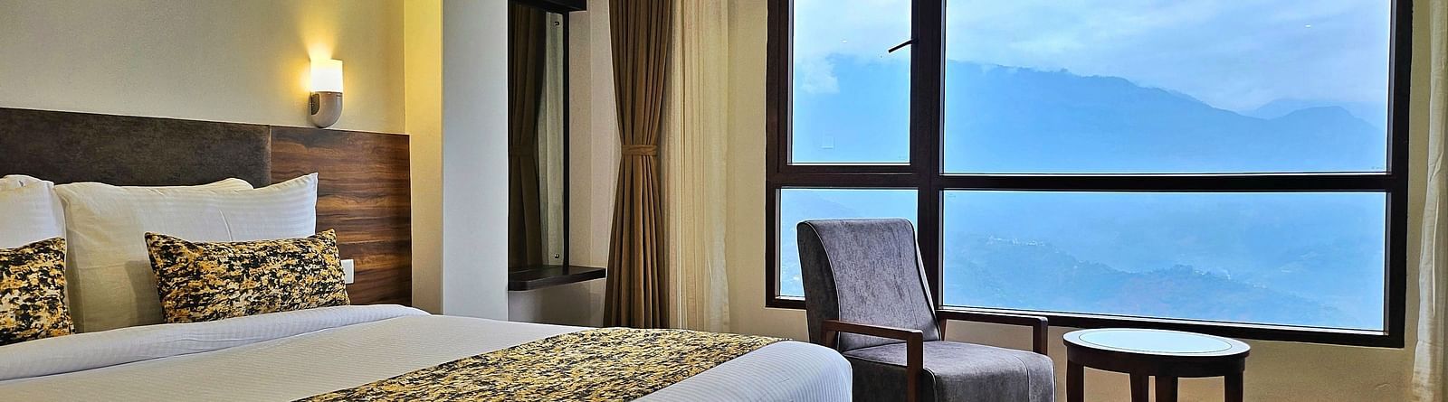 view of king size bed and chairs near the window of Premium Room at Sumitel Pelling, Geyzing