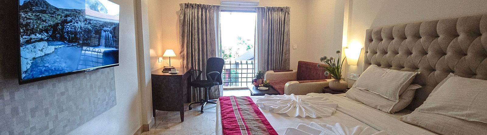 A bright room with an elegant bed, seating area, and access to a balcony – The Verda de Miranda Resort.