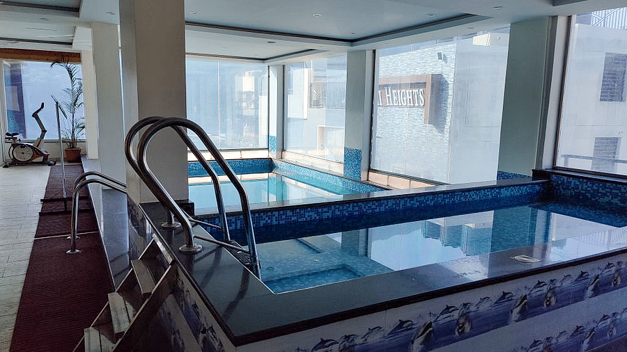 The indoor swimming pool with huge glass windows overlooking the neighbouring buildings at Regenta Inn DLS.