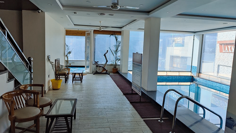 The common area besides the swimming pool with two chairs along with a coffee table at Regenta Inn DLS.