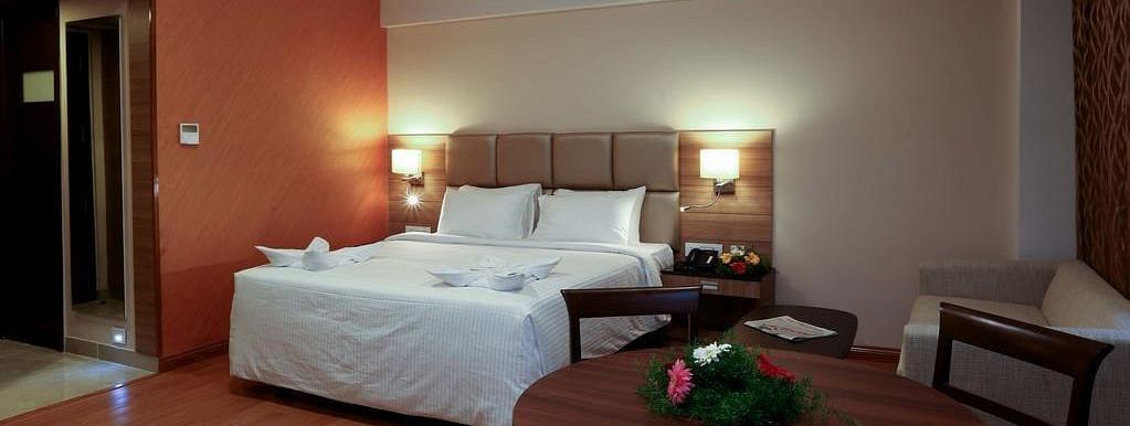 Room with bed and a table with flowers on top at Fressotel Seetharam, Coimbatore