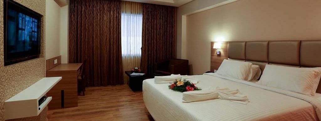 Spacious room with television, bed and table at Fressotel Seetharam, Coimbatore