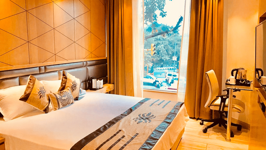 A Superior Room at JRD Pride - Business Hotel featuring a well-made bed, an accent wall, a work desk, and a large glass window. 