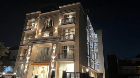 Multiple storey building exterior of Lime Tree Hotels & Service Apartment Private Limited illuminated against a dark night sky.