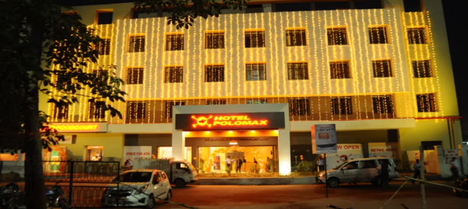 Facade shot of Max Hotel Prayagraj building illuminated at night, with a grand entrance and warm lighting.