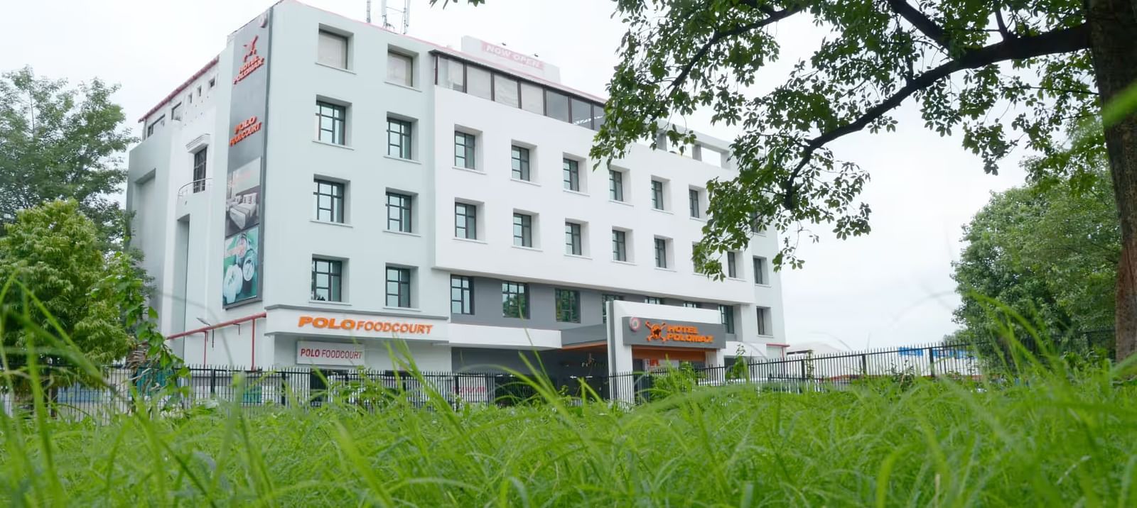 Facade view of Max Hotel Prayagraj with lush green garden in the front and clear sky in the background.