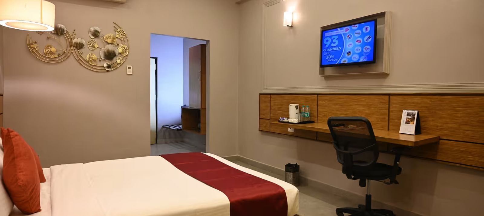 View of a hotel room featuring a workspace with a desk, chair, and wall-mounted TV - Max Hotel Prayagraj.