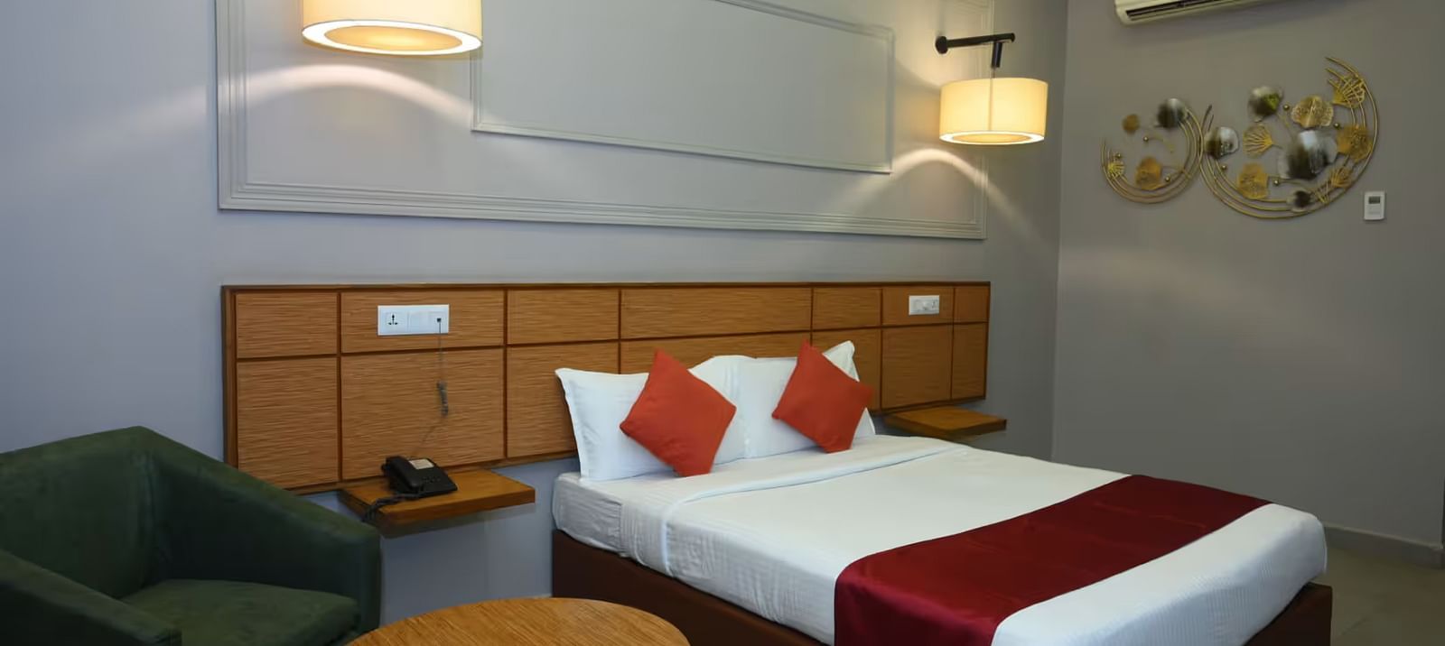 View of an elegant hotel room with a king size bed, warm lighting, and a cosy seating - Max Hotel Prayagraj.