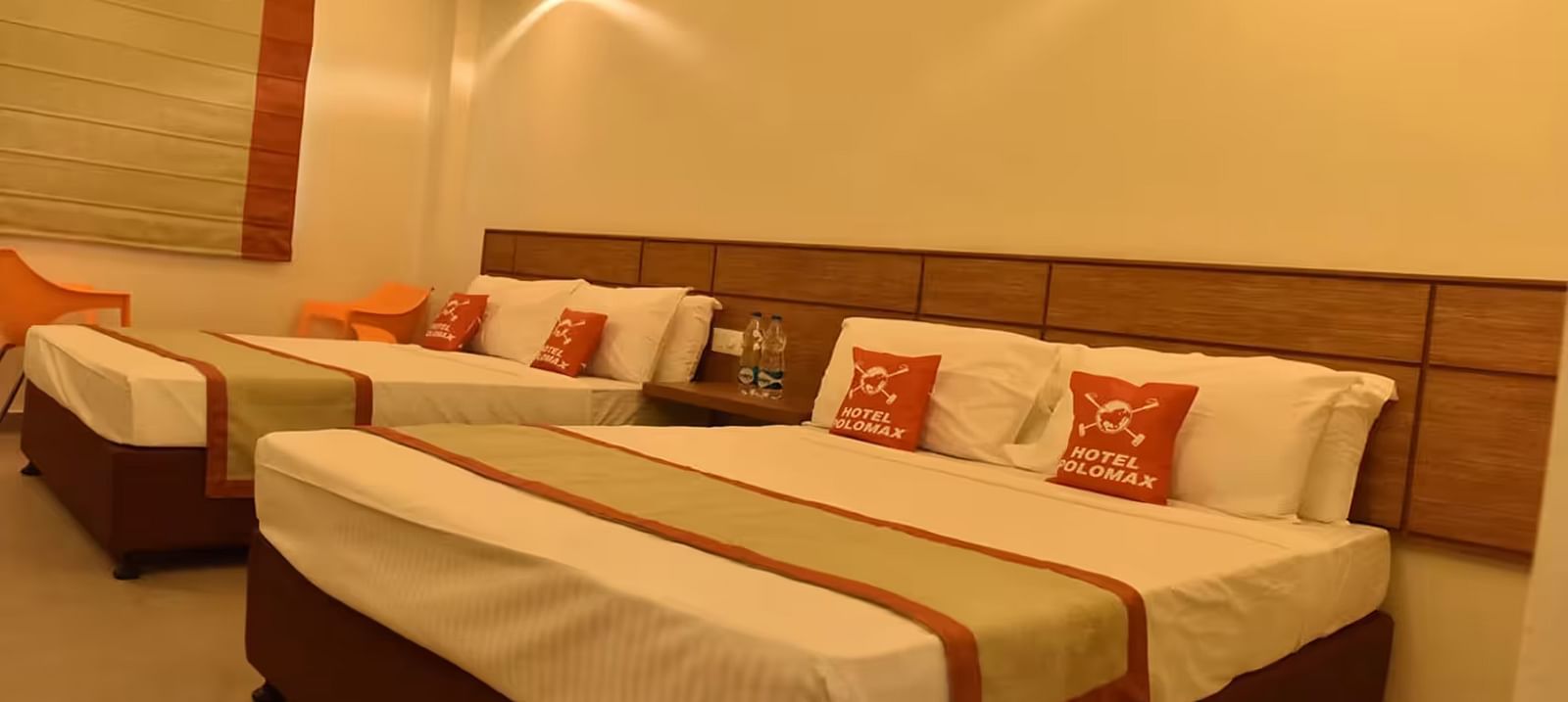 View of a hotel room with multiple beds, soft lighting, and cosy interiors - Max Hotel Prayagraj.