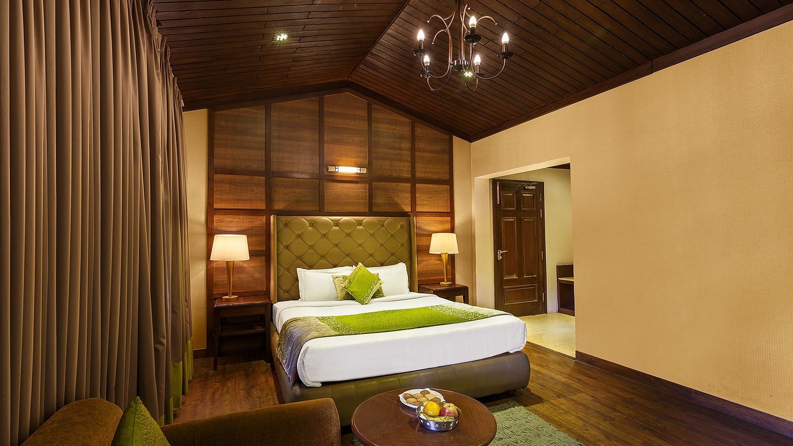 a bedroom with a large bed and side lamps, a table and a sofa - The Earl's Court, Nainital
