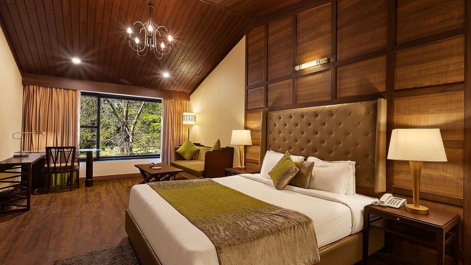 A bedroom with a large bed and a workdesk and chairs on the corner of the room, with large windows with trees visible - The Earl's Court, Nainital