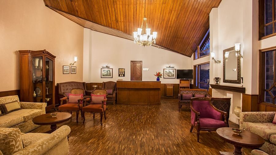 A image featuring interior view of lobby area at the naini retreat, nainital. with wooden flooring and roofing, with a chandelier lit.