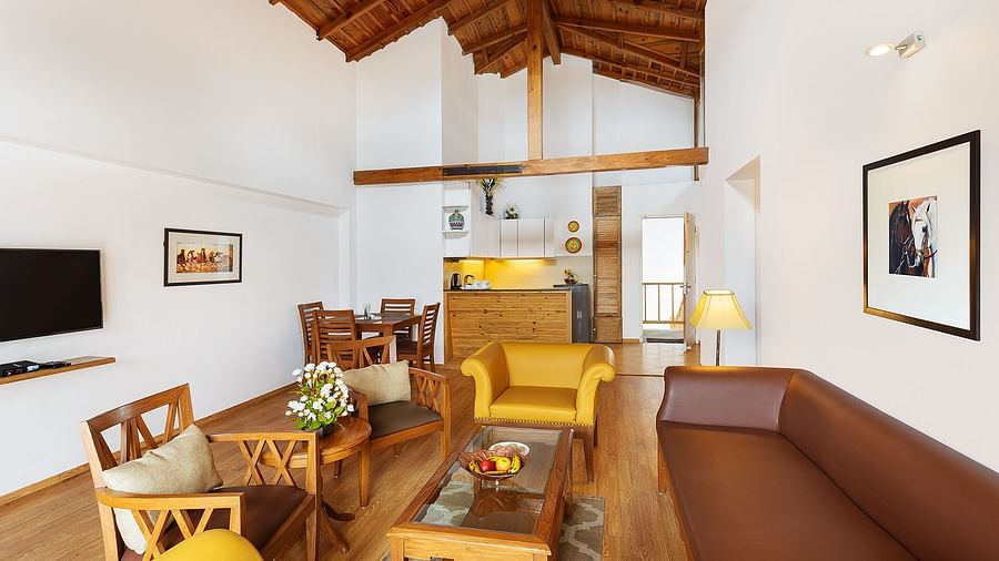 Living room with comfortable sofa and chair with attached kitchenette of Two Bedroom Apartment - The Pinewood Nainital