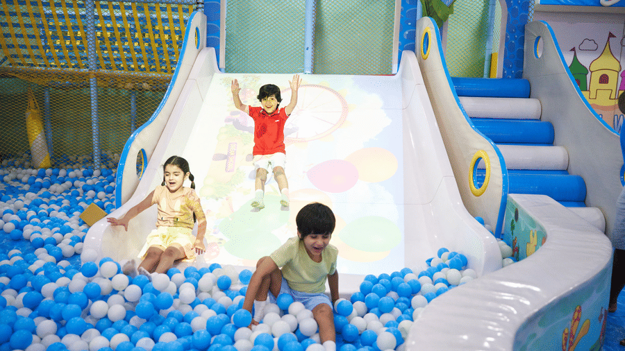 Children cheerfully slide down into a massive ball pit at the Tic Tac Tot indoor playground.