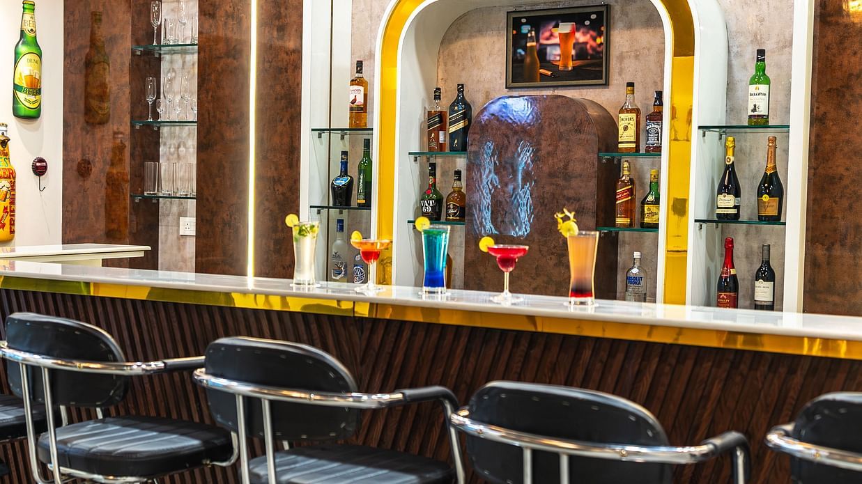 bar counter with bottles kept on the shelf and chairs arranged