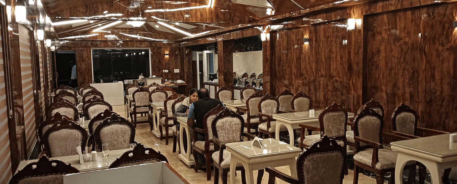 A well-lit multi-cuisine restaurant with wooden interiors and cosy dining setup for guests - Benzz Park, Kodaikanal
