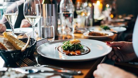 A beautifully set dining table featuring food served on a plate, accompanied by glasses and a candle