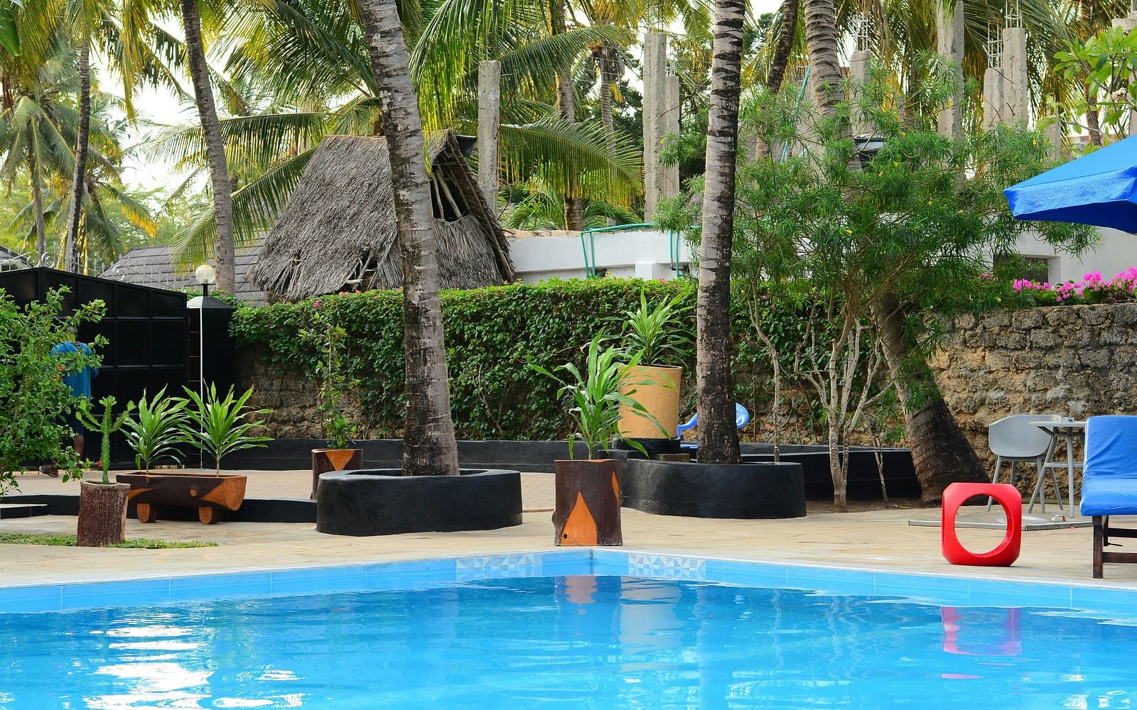 A swimming pool with outdoor seating area besides it along with lush green surroundings.