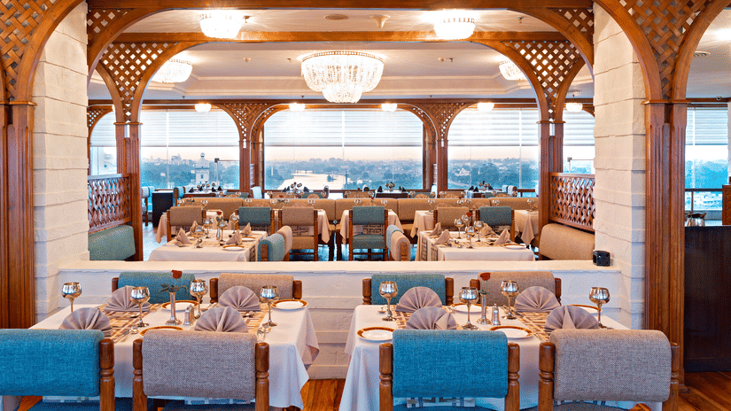 A vibrant, stylish Fine-Dine Restaurant in Lucknow with a modern, lattice-style ceiling and large windows overlooking a scenic view at Clarks Avadh, Lucknow - One of the Best Restaurants in Lucknow.