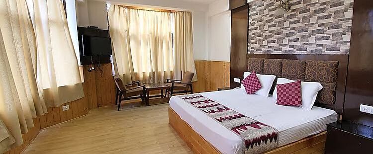 A view of a room at DLS Hotel Devlok, Manali with a double bed, a television and large windows