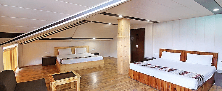 A room at DLS Hotel Devlok, Manali with a sloping roof line alongside a sofa chair and a coffee table