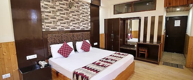 A view of a room at DLS Hotel Devlok, Manali with a double bed, side tables, a wardrobe and a dressing mirror