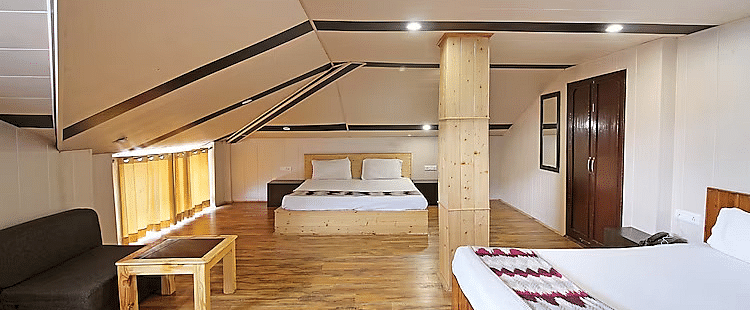 A room at DLS Hotel Devlok, Manali with a double bed and a sofa chair and a coffee table placed in front of it