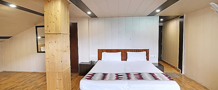 A room at DLS Hotel Devlok, Manali with a double bed and a beam right beside it