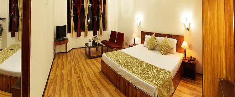 A room at DLS Hotel Devlok, Manali with a double bed, side tables, a wardrobe and wooden flooring