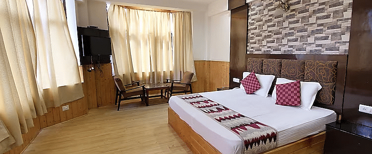 A view of a room at DLS Hotel Devlok, Manali with a double bed, a television and large windows