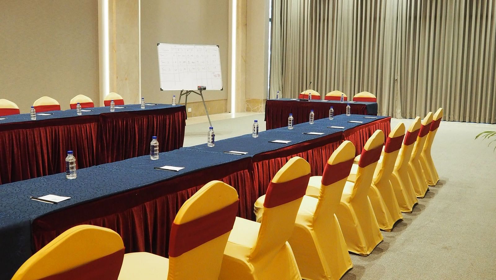 A long table with yellow chairs in a brightly lit, spacious conference hall - Club Charholi, Pune 