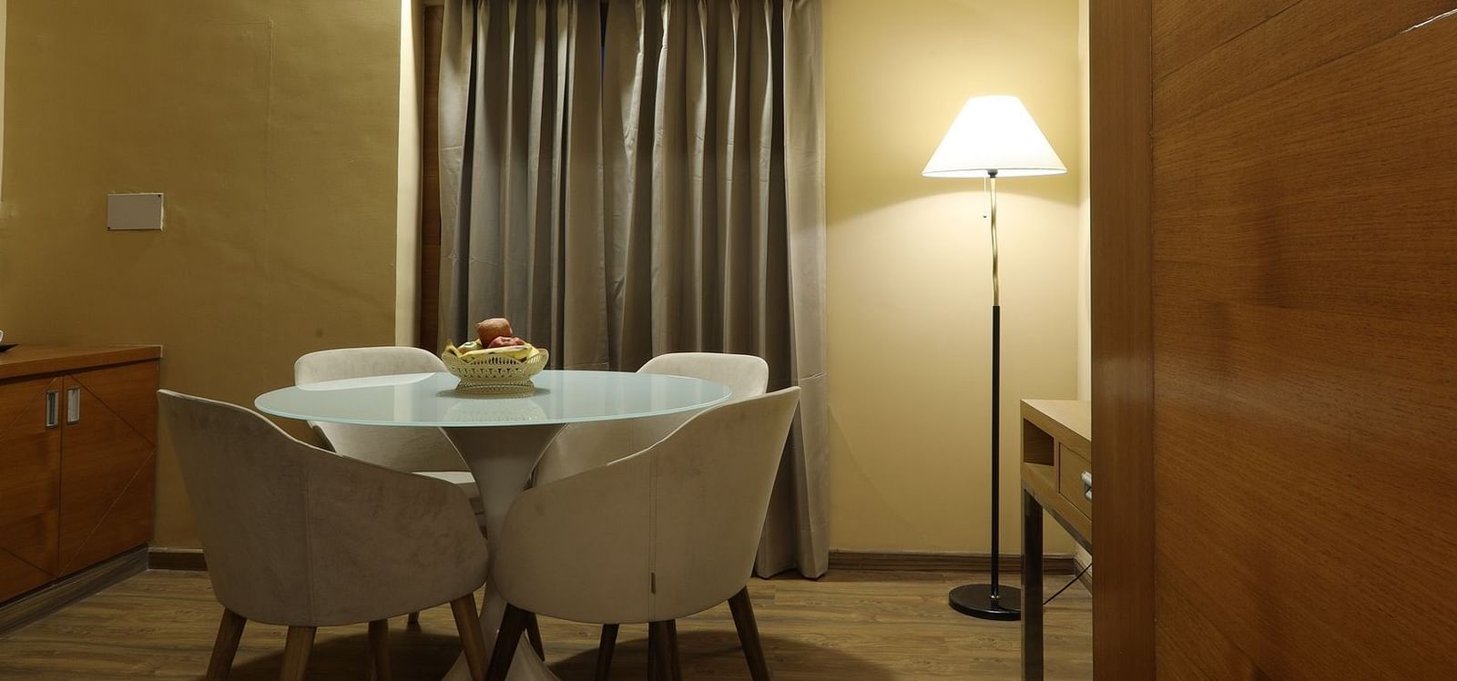 Hotel room interior with a small seating area, fan, and a view through a window, Rang Lords Inn Bharuch