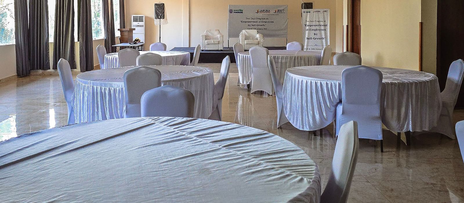 Event space set up with white-covered round tables and natural lighting at The Verda de Miranda Resort.