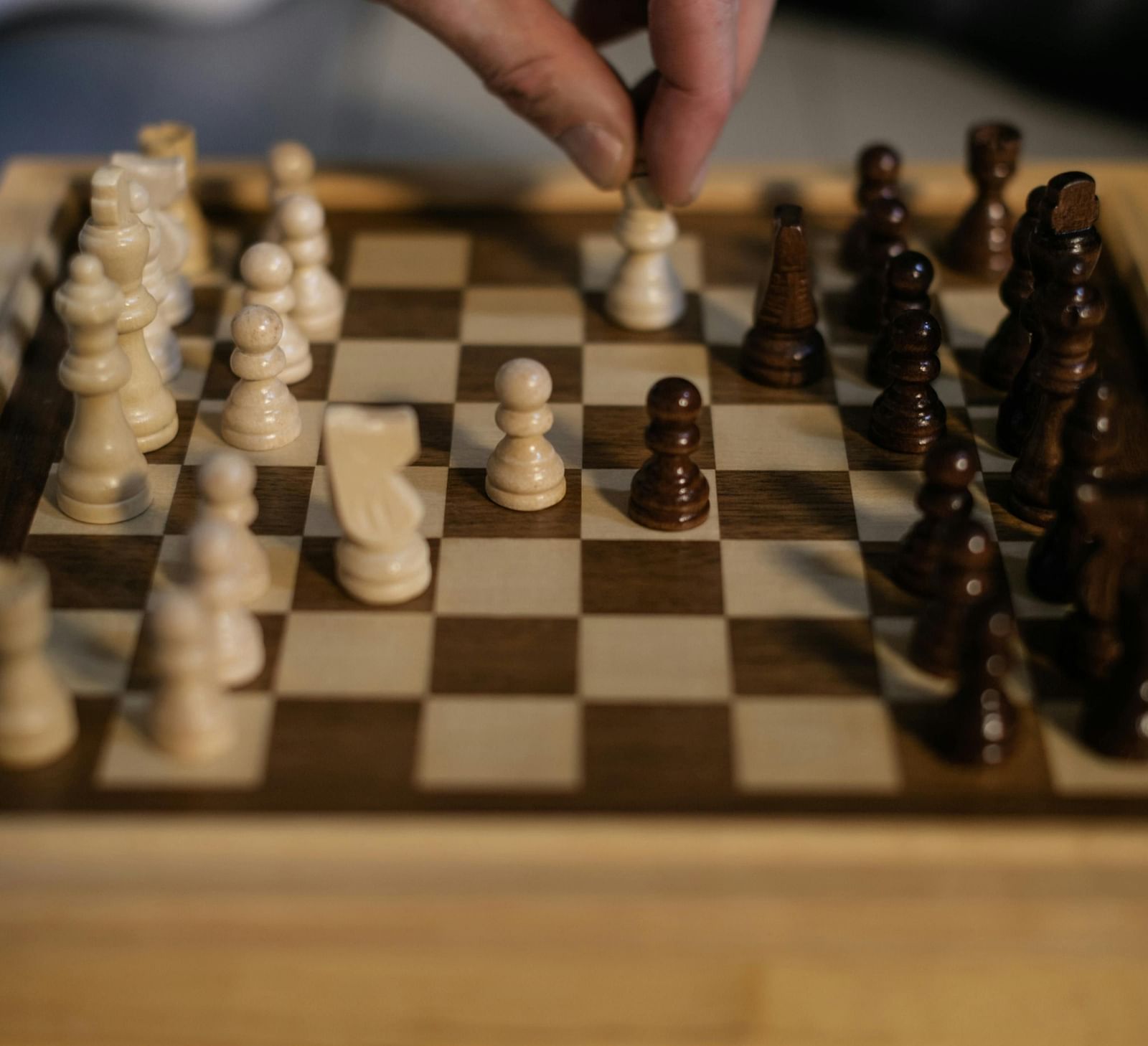 image featuring a wooden chess board with two people playing chess on it