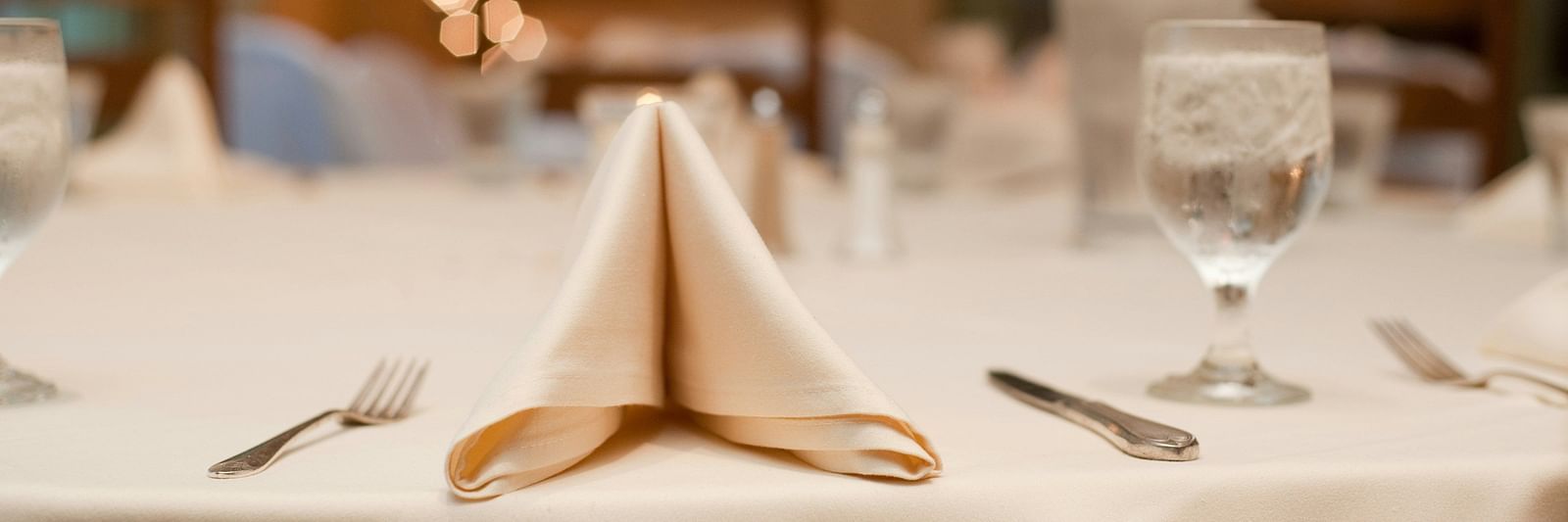 A table in a banquet hall with a napkin and cutlery placed on it