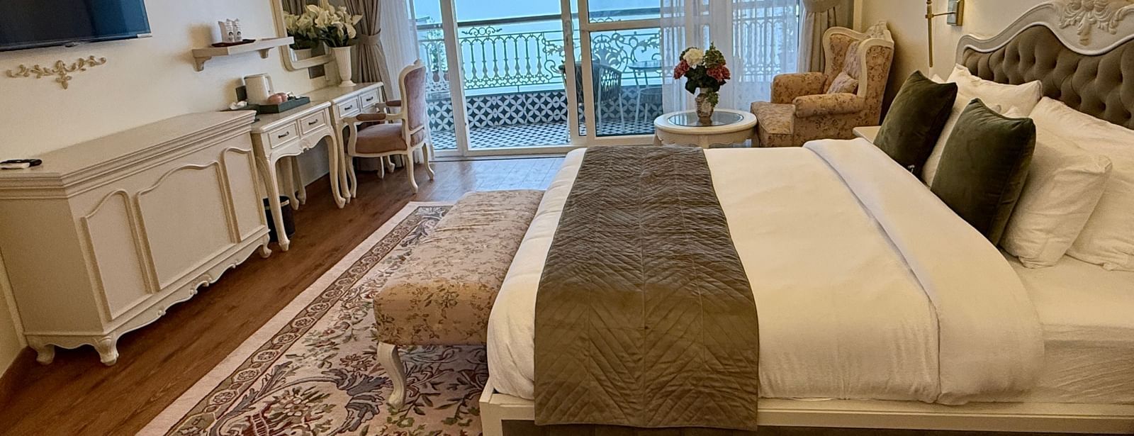 Spacious bedroom with a plush queen size bed, vintage decor, and balcony access - Mayfair Cafe & Suites, Dalhousie