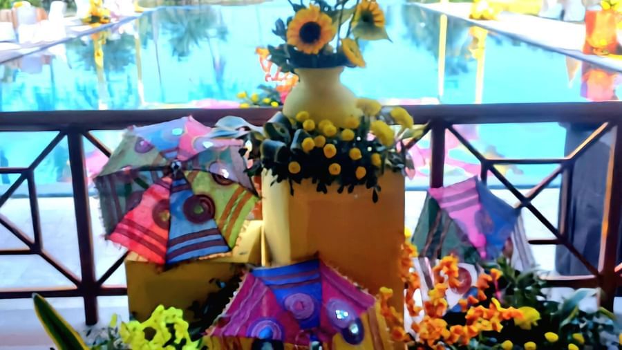 A decorated outdoor area, possibly for an event, features floral arrangements, a statue, and a pool in the background