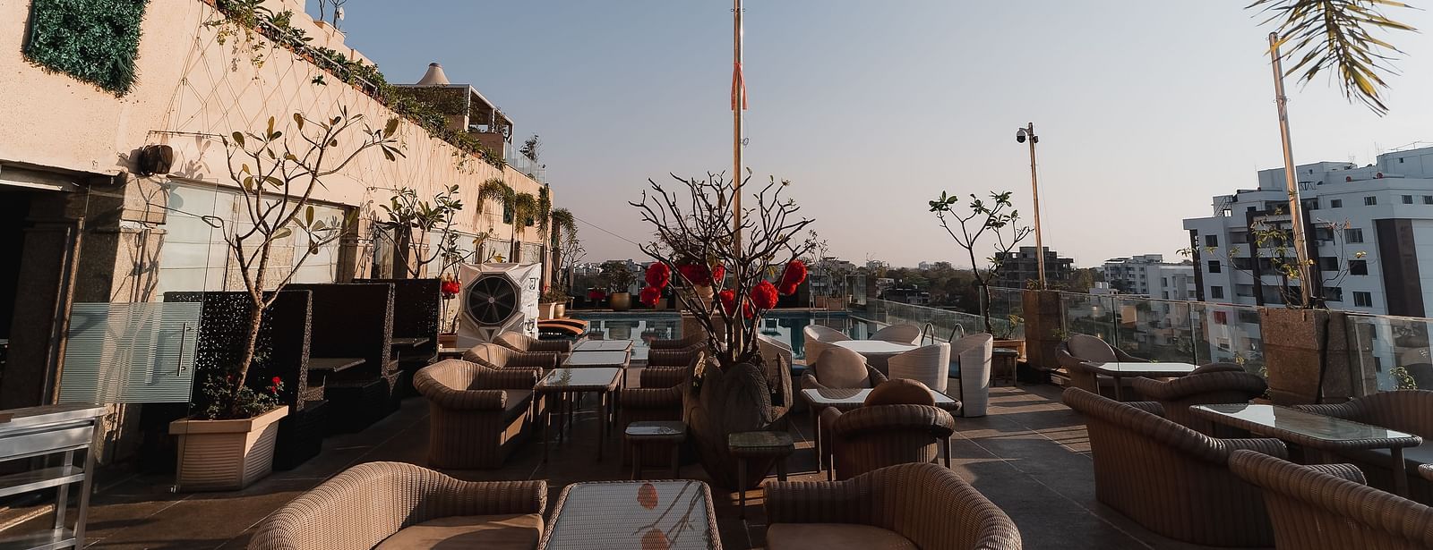 An outdoor dining setup at Hotel Ashok Nagpur with cushioned chairs around tables.